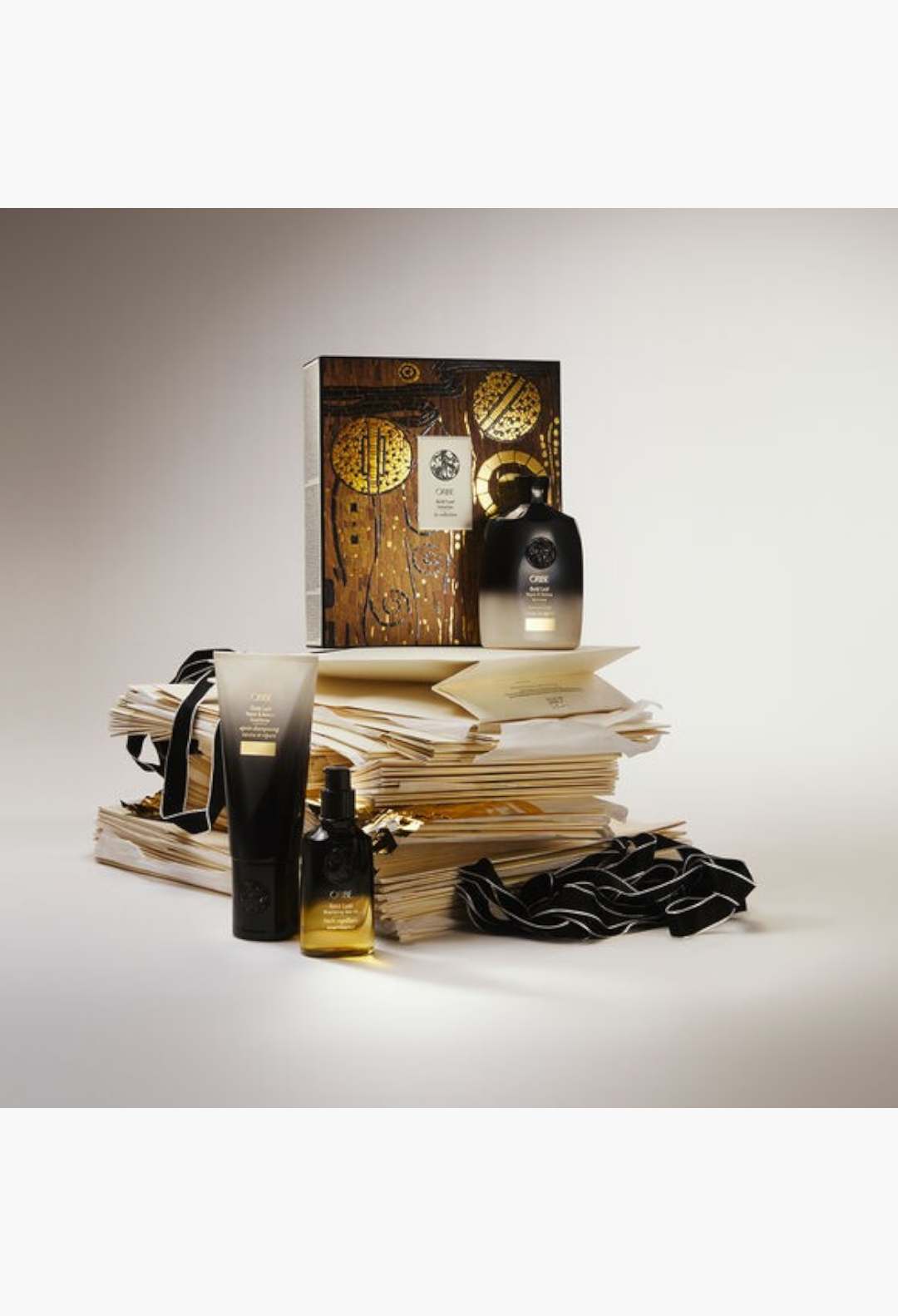 GLAM MODA Oribe Gold Lust haircare gift set featuring shampoo, conditioner, and nourishing hair oil in luxury packaging.