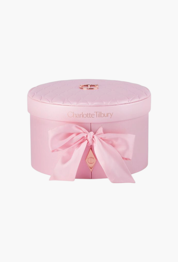 GLAM MODA Charlotte Tilbury Pillow Talk Dreams Come True vanity box in a round, quilted pink case with a satin bow.