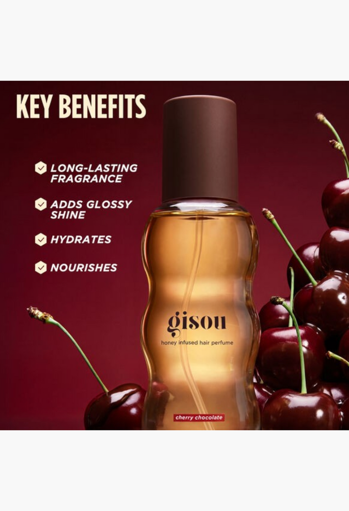 GLAM MODA Gisou Cherry Chocolate hair perfume bottle surrounded by fresh cherries on a deep red background