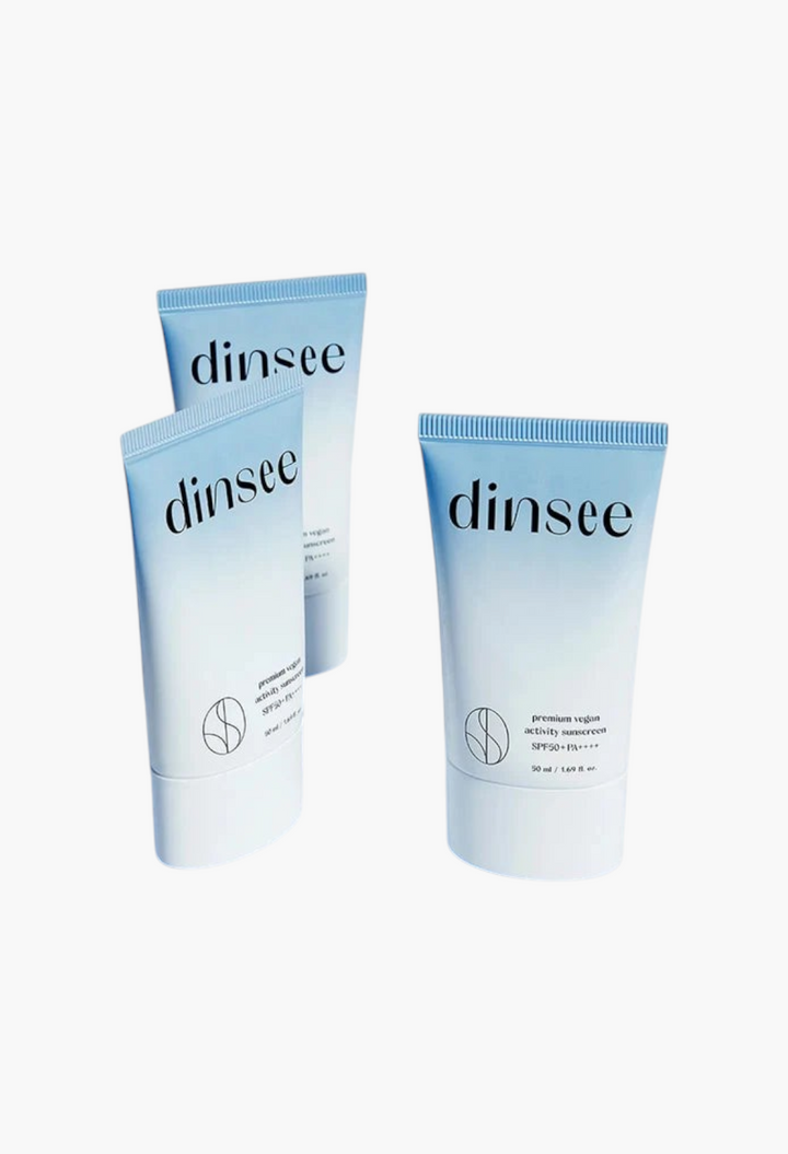 GLAM MODA Dinsee vegan SPF50+ sunscreen tubes with a white cream swatch on a light blue background.