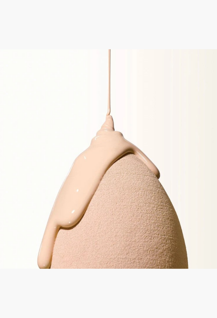 GLAM MODA Goodal Heartleaf BB cream in neutral beige shade dripping onto a soft makeup sponge for smooth application