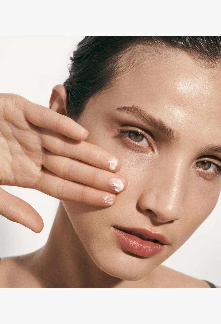 GLAM MODA The Moisturizing Soft Cream applied to a woman's cheek for a radiant and hydrated complexion