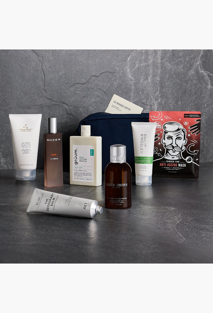 GLAM MODA GLOSSYBOX Grooming Kit featuring skincare and haircare products in a navy bag on a dark stone surface.