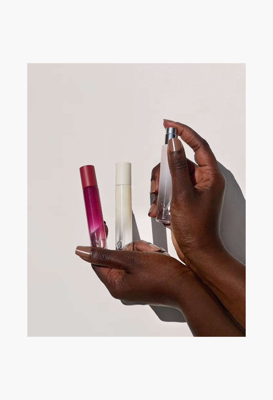 GLAM MODA Glossier You Doux eau de parfum spray bottles held in hands, showcasing the woody skin-scent fragrance.