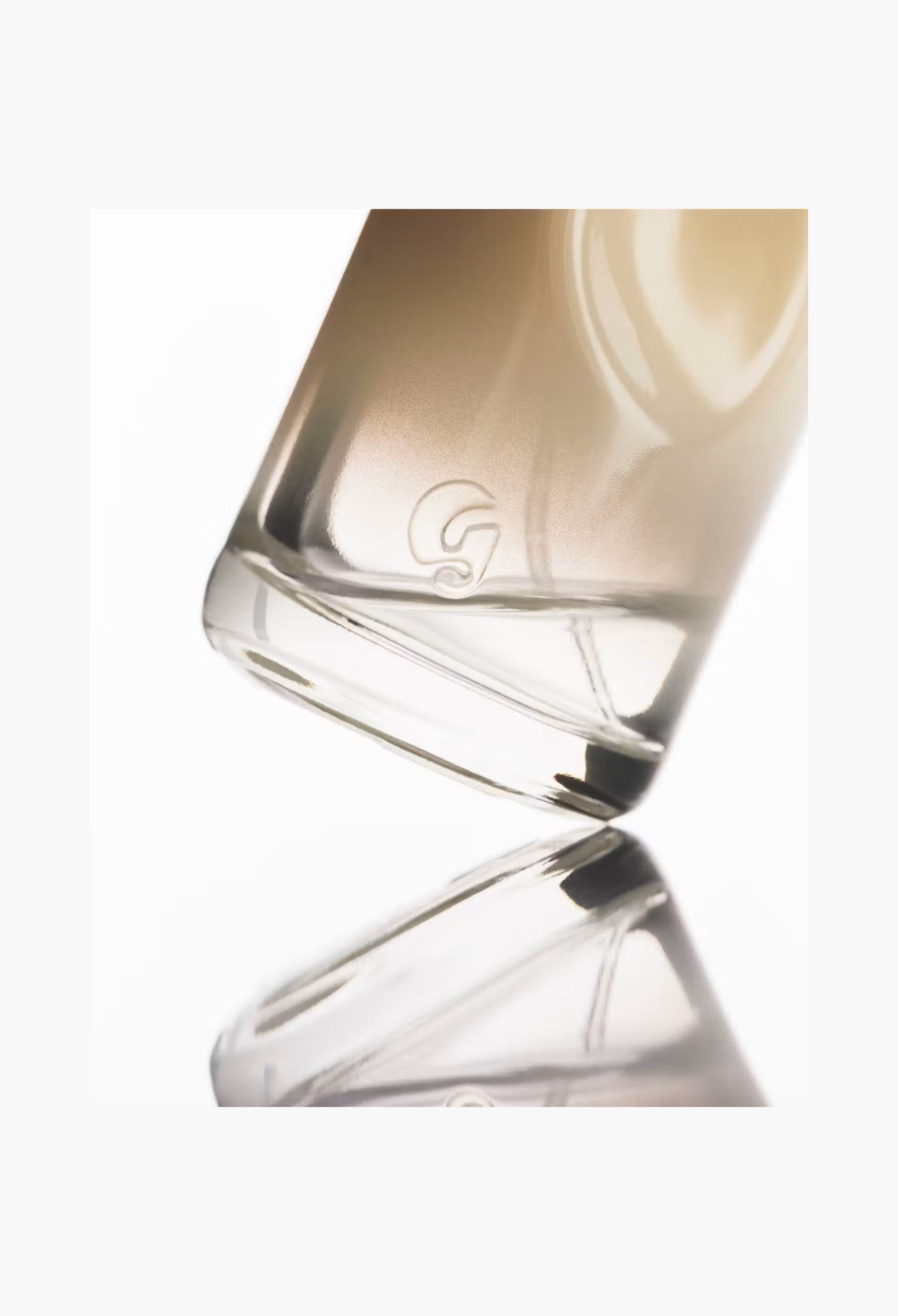 GLAM MODA Glossier You Doux woody eau de parfum glass bottle with embossed G logo on a reflective white surface