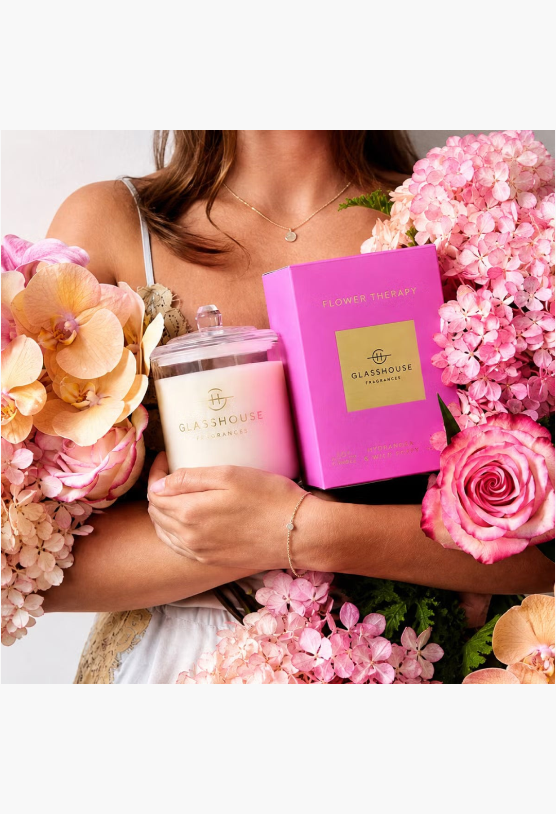 GLAM MODA Glasshouse Fragrances Flower Therapy soy candle in a glass jar with a pink gift box held by a woman
