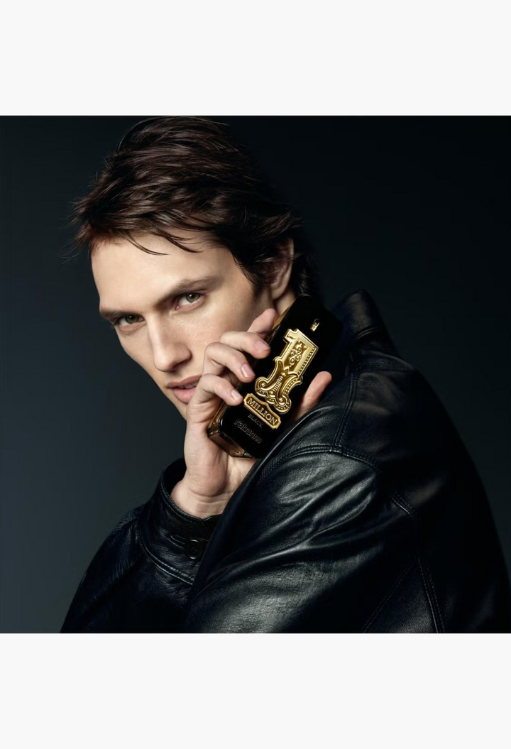 GLAM MODA model holding a black and gold Rabanne 1 Million Black Eau de Parfum bottle while wearing a leather jacket.