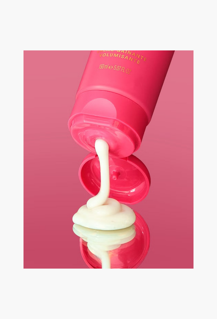 GLAM MODA Hair By Sam McKnight Cool Girl Volumising Cream in a pink tube dispensing white hair styling product