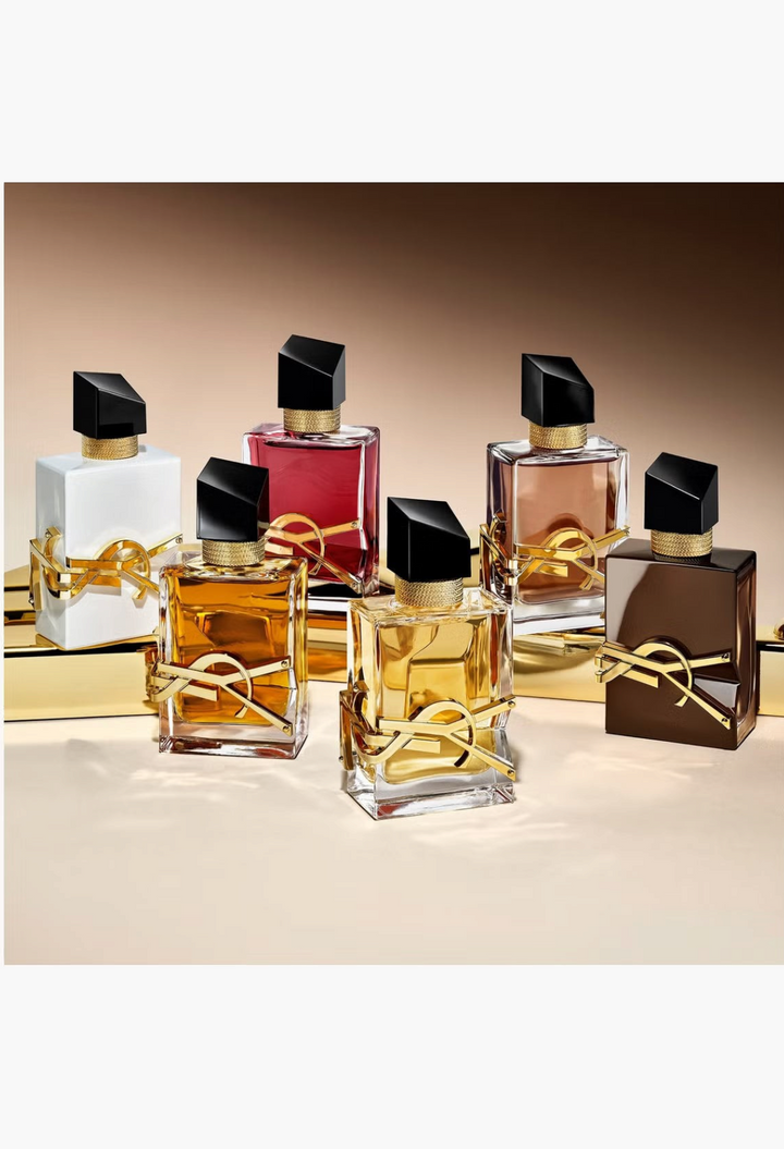 GLAM MODA collection of YSL Libre perfume bottles in various colours with iconic gold logos on a gold platform.