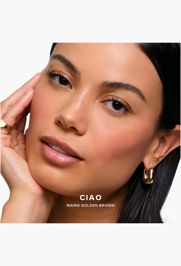 GLAM MODA model wearing Saie SuperSuede Radiant Blush in Ciao, a warm golden brown shade with a soft-focus finish.