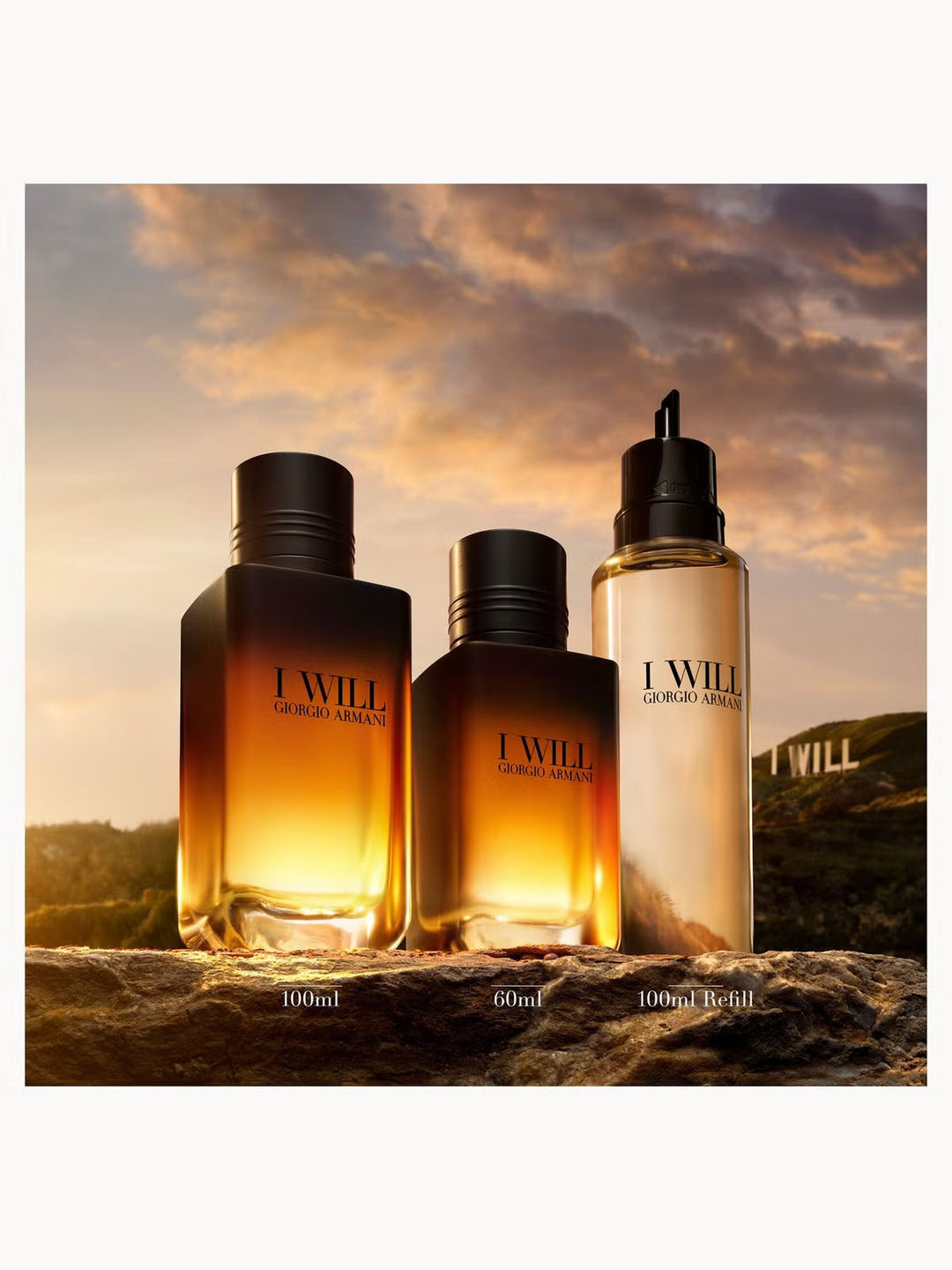 GLAM MODA Giorgio Armani I Will Eau de Parfum bottles in 100ml, 60ml, and 100ml refill sizes on a rocky landscape.