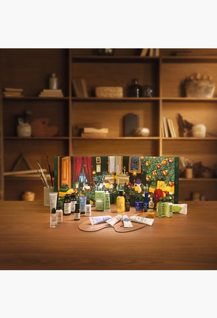 GLAM MODA L'Occitane beauty advent calendar featuring 24 skincare and body care minis displayed on a wooden table.