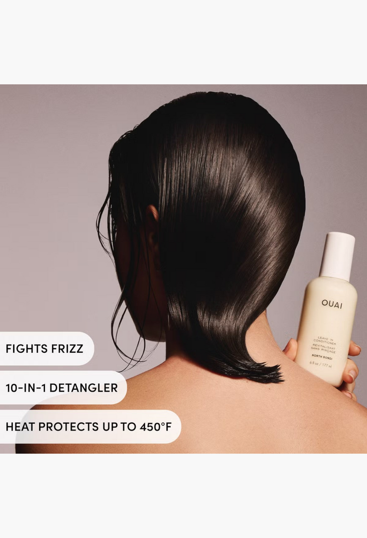 GLAM MODA OUAI Leave In Conditioner bottle held by a person with sleek, dark hair against a white background.