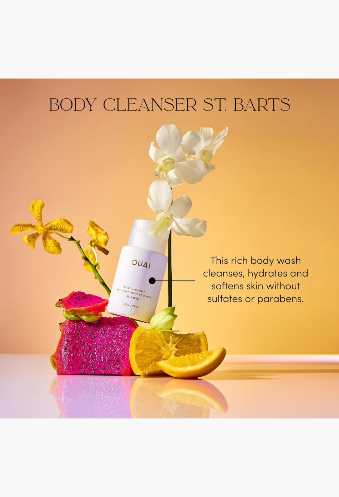 GLAM MODA OUAI St. Barts Body Cleanser bottle surrounded by dragon fruit, orange slices, and white orchid flowers.