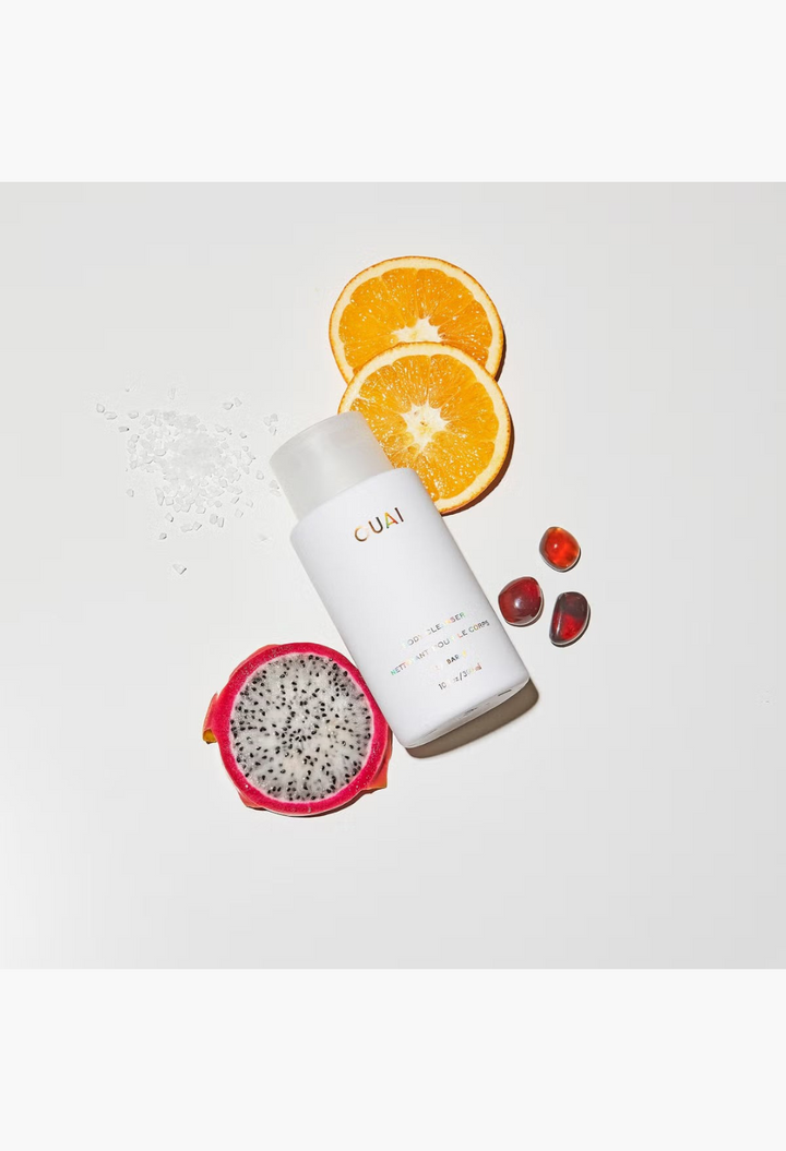 GLAM MODA OUAI St. Barts Body Cleanser bottle surrounded by orange slices, dragon fruit, and sea salt on white surface
