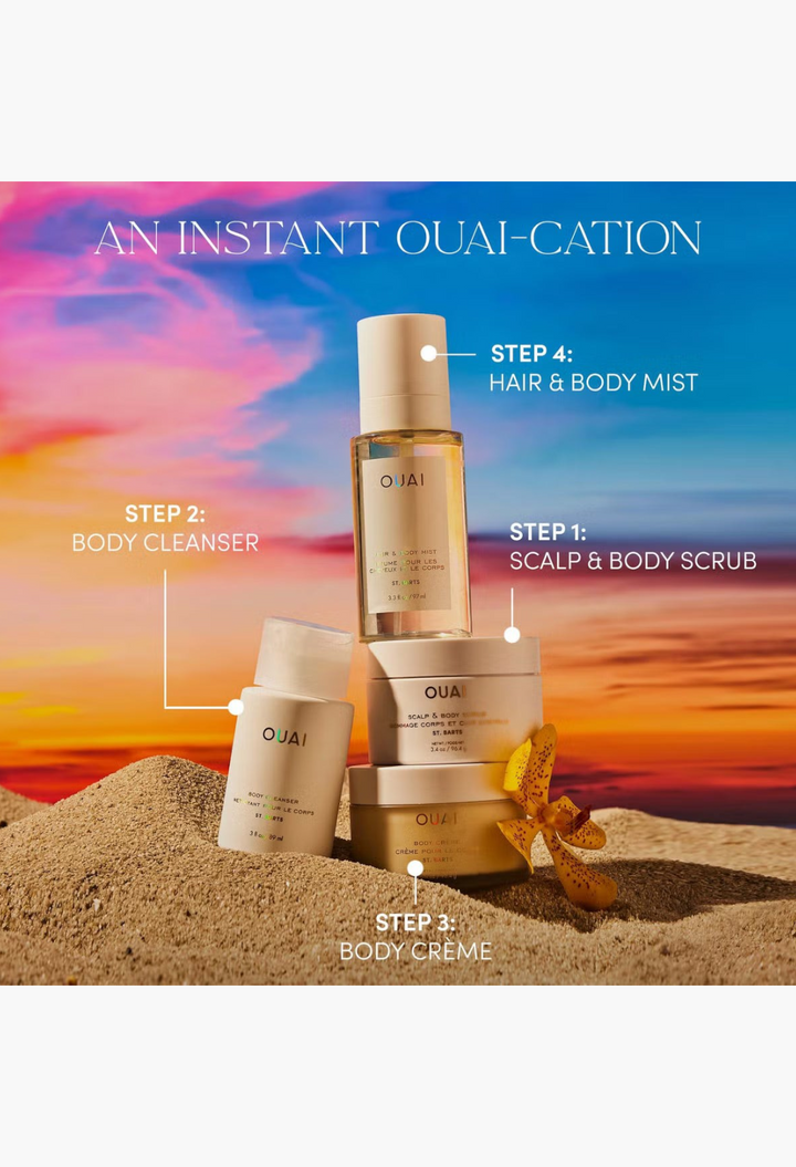 GLAM MODA collection of OUAI St. Barts body care products including cleanser, scrub, creme, and mist on sandy beach