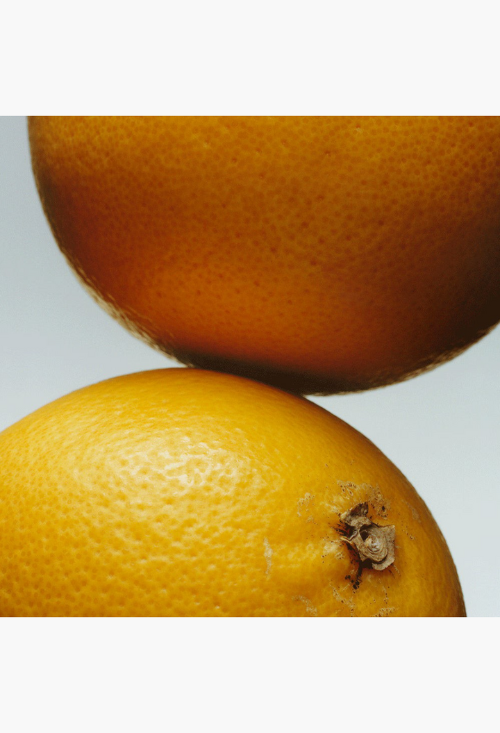 GLAM MODA Grapefruit Cologne featuring a close-up of fresh, textured citrus fruit skins in bright morning light.