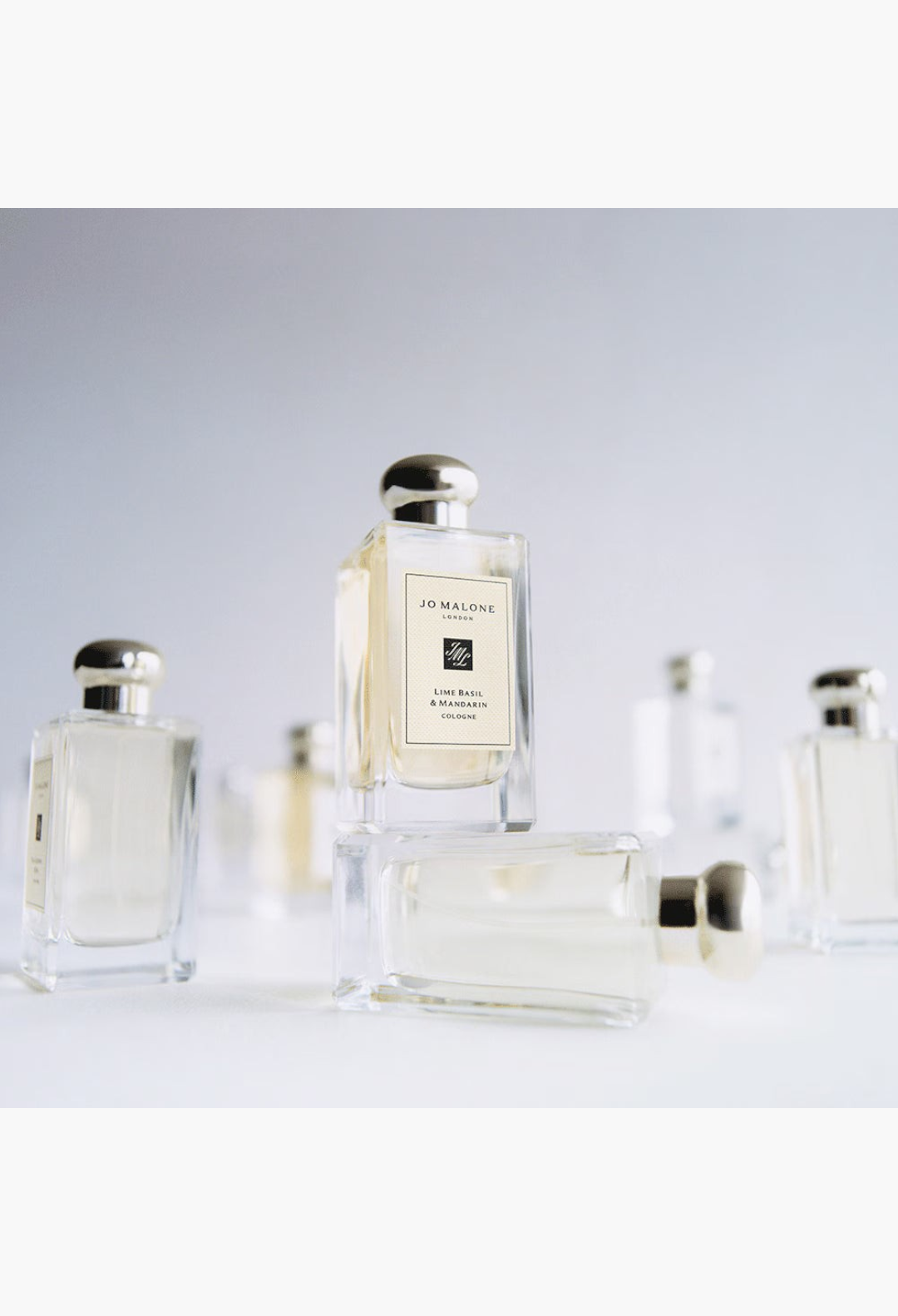 GLAM MODA Grapefruit Cologne glass perfume bottles with silver caps arranged in a minimalist studio setting.