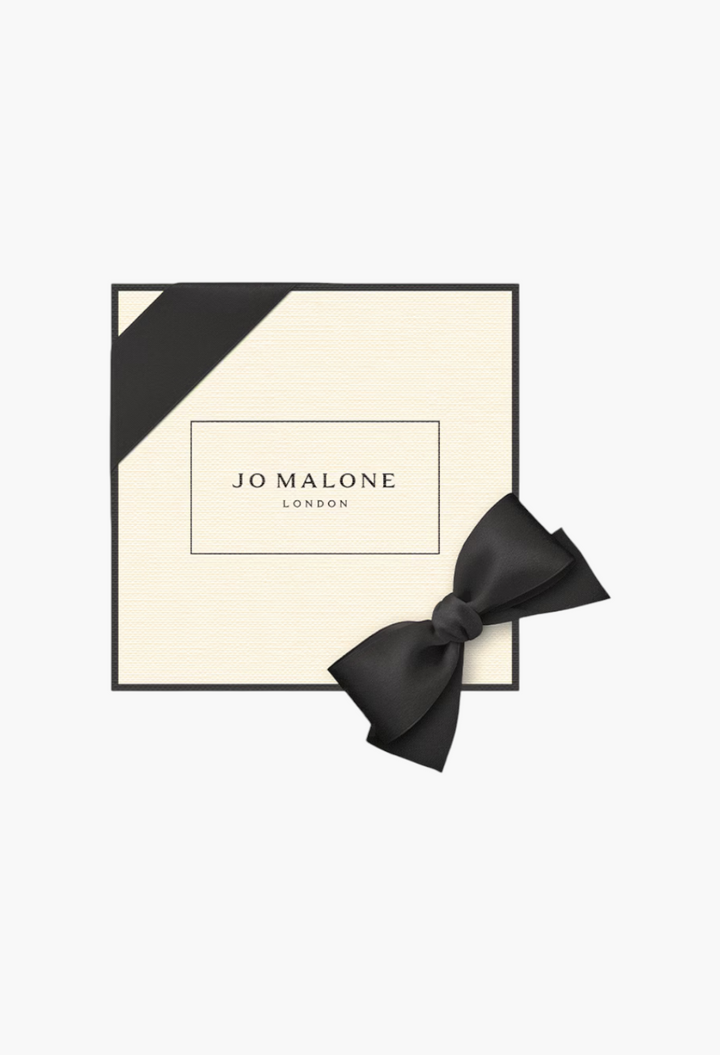 GLAM MODA Jo Malone London English Oak & Hazelnut cologne gift box in cream with black trim and a black satin bow.