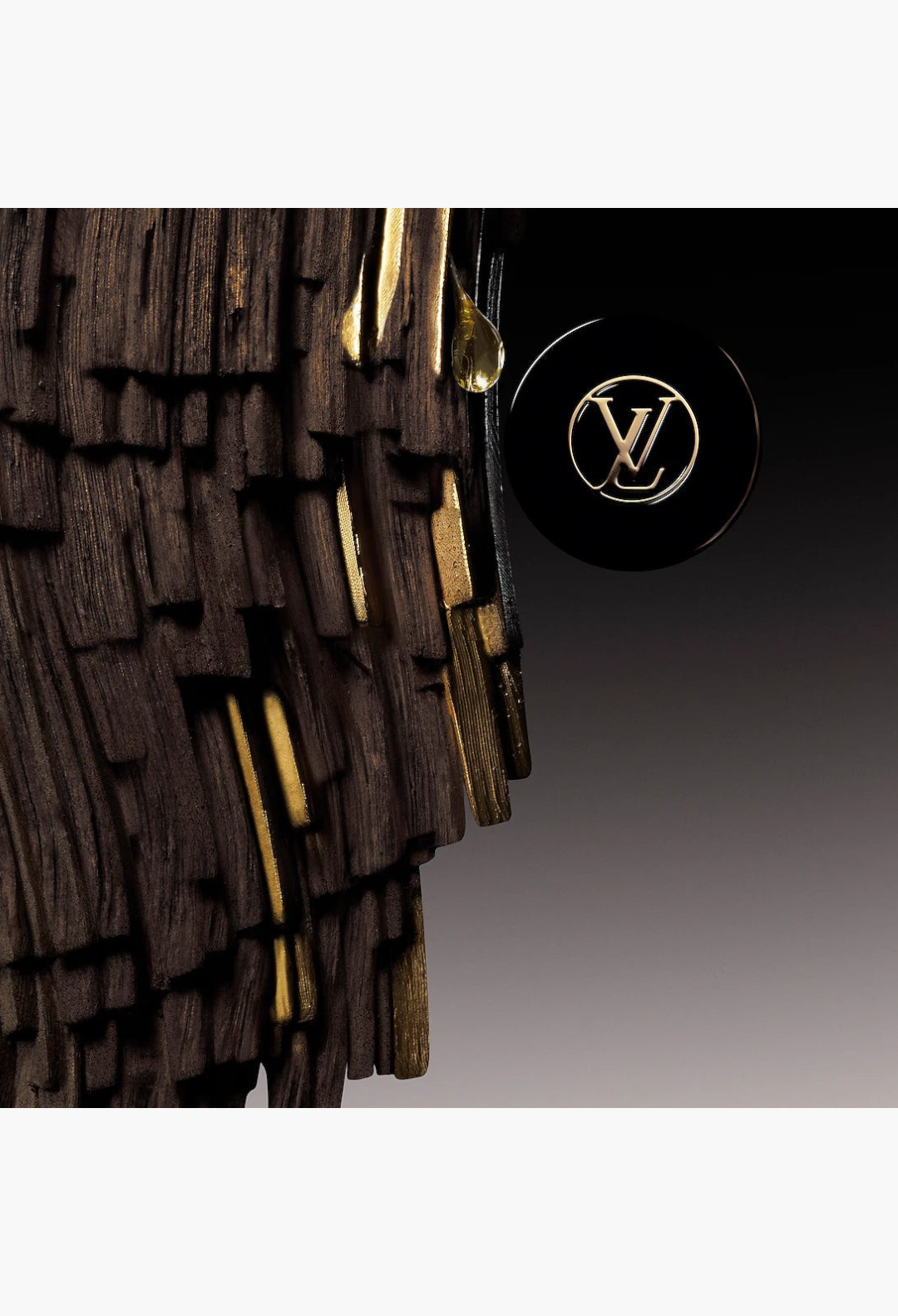 GLAM MODA Pur Oud perfume bottle cap with gold logo against a textured dark wood background with a single drop of oil.