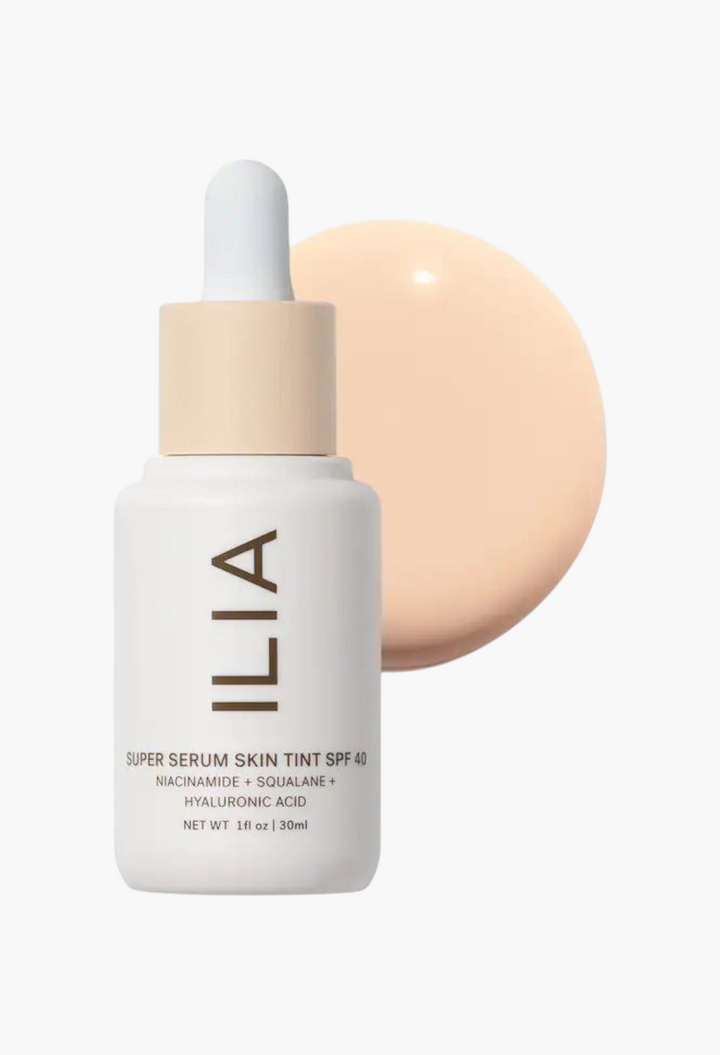 GLAM MODA ILIA Super Serum Skin Tint SPF 40 bottle with a swatch of light liquid foundation on a white background.