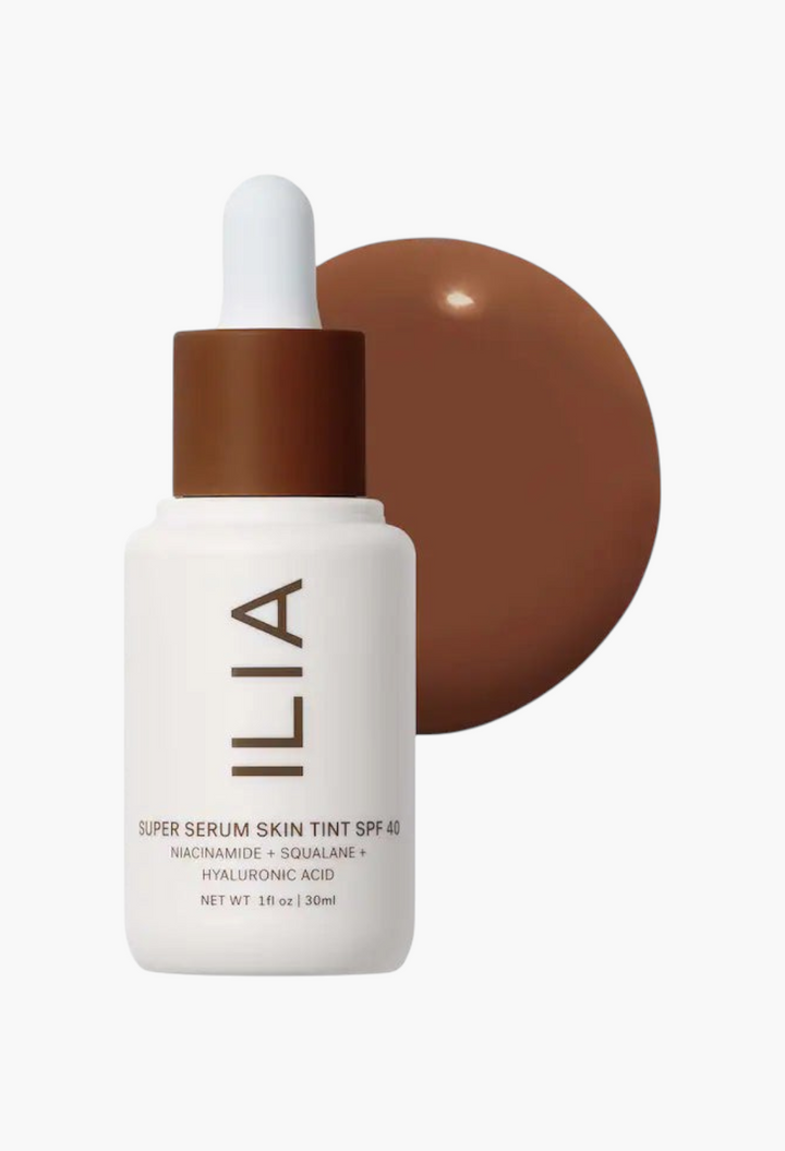 GLAM MODA ILIA Super Serum Skin Tint SPF 40 in a white dropper bottle with a swatch of dark liquid foundation.