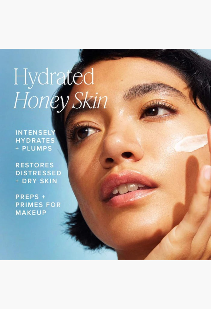 GLAM MODA Honey Halo moisturizer applied to a model's cheek for hydrated, plump skin against a blue background.