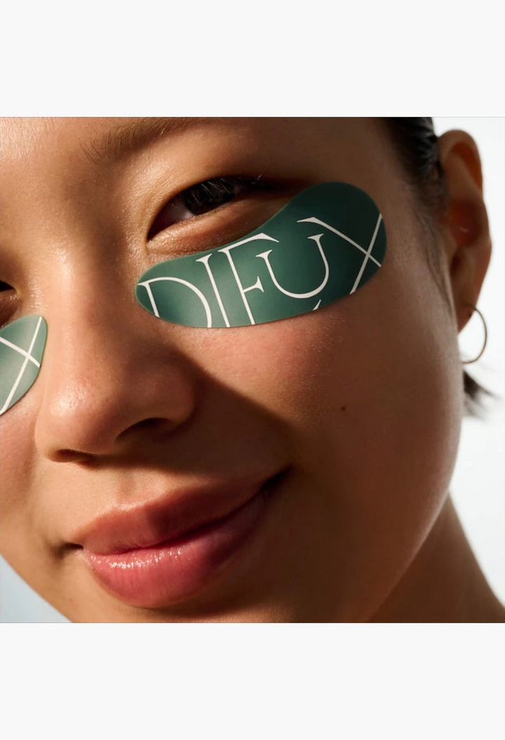 GLAM MODA reusable silicone eye masks in dark green applied under the eyes of a smiling woman for hydration.