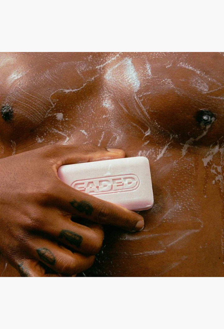 GLAM MODA Faded brightening body bar held against soapy skin to treat dark spots and uneven skin tone.