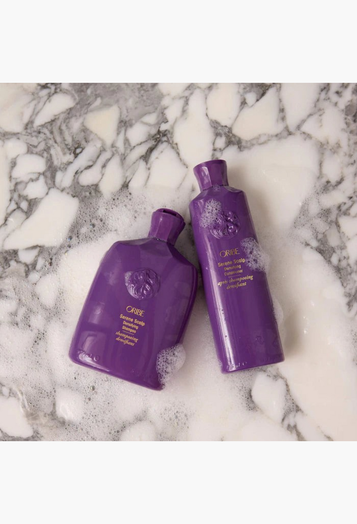 GLAM MODA Serene Scalp densifying shampoo and conditioner bottles on a marble surface with soap bubbles