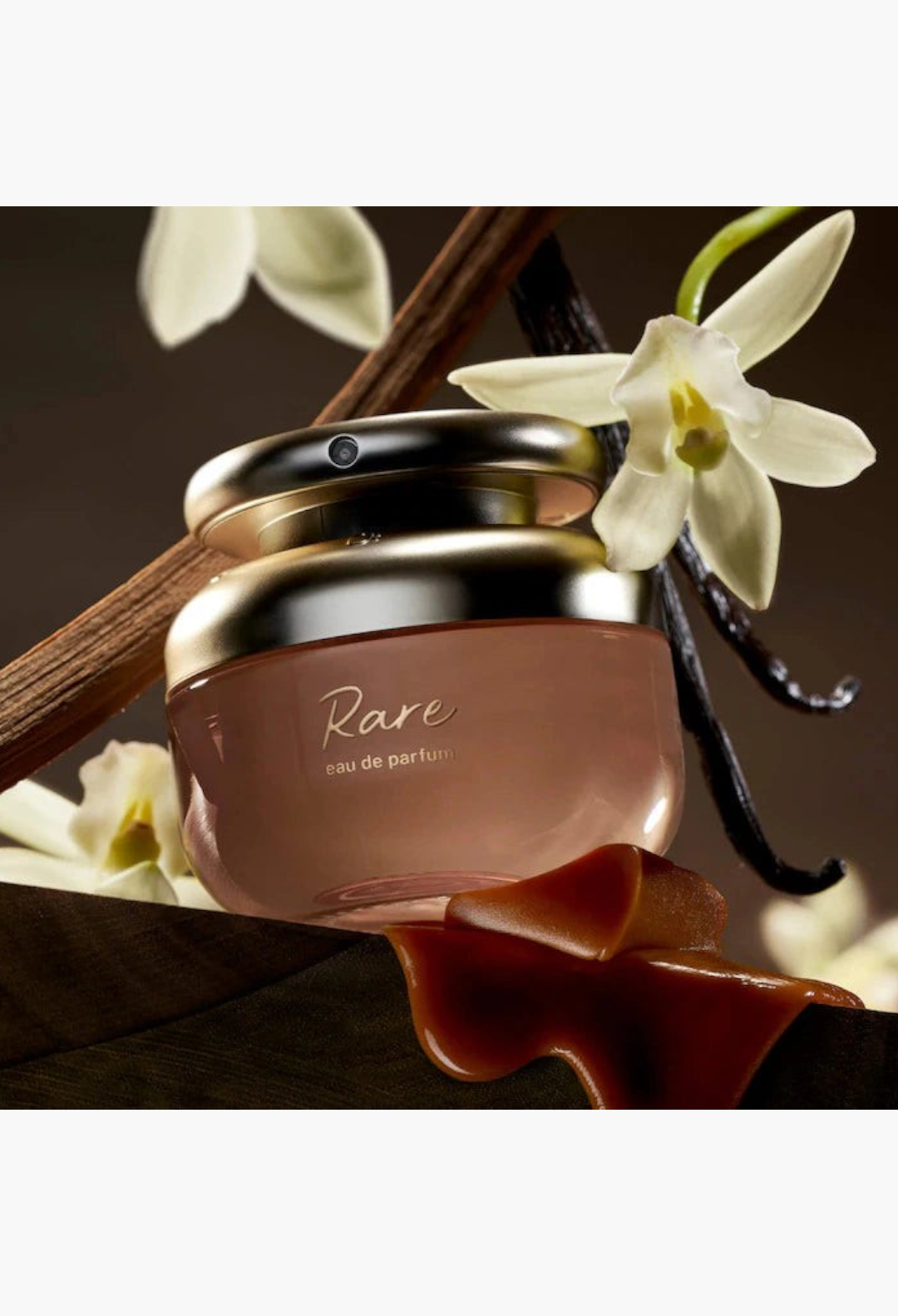 GLAM MODA Rare Beauty perfume bottle with vanilla bean and flower accents on a clean background
