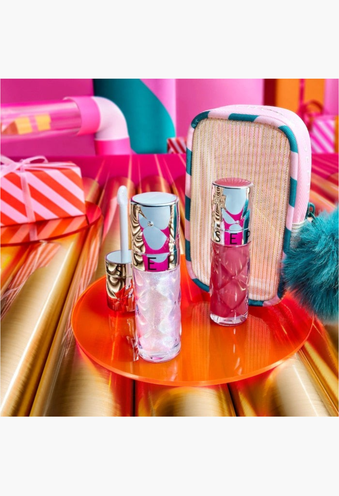 GLAM MODA Outrageous Lip Plumper duo set featuring a shimmering cosmic gloss, a rosewood gloss, and a festive pouch.