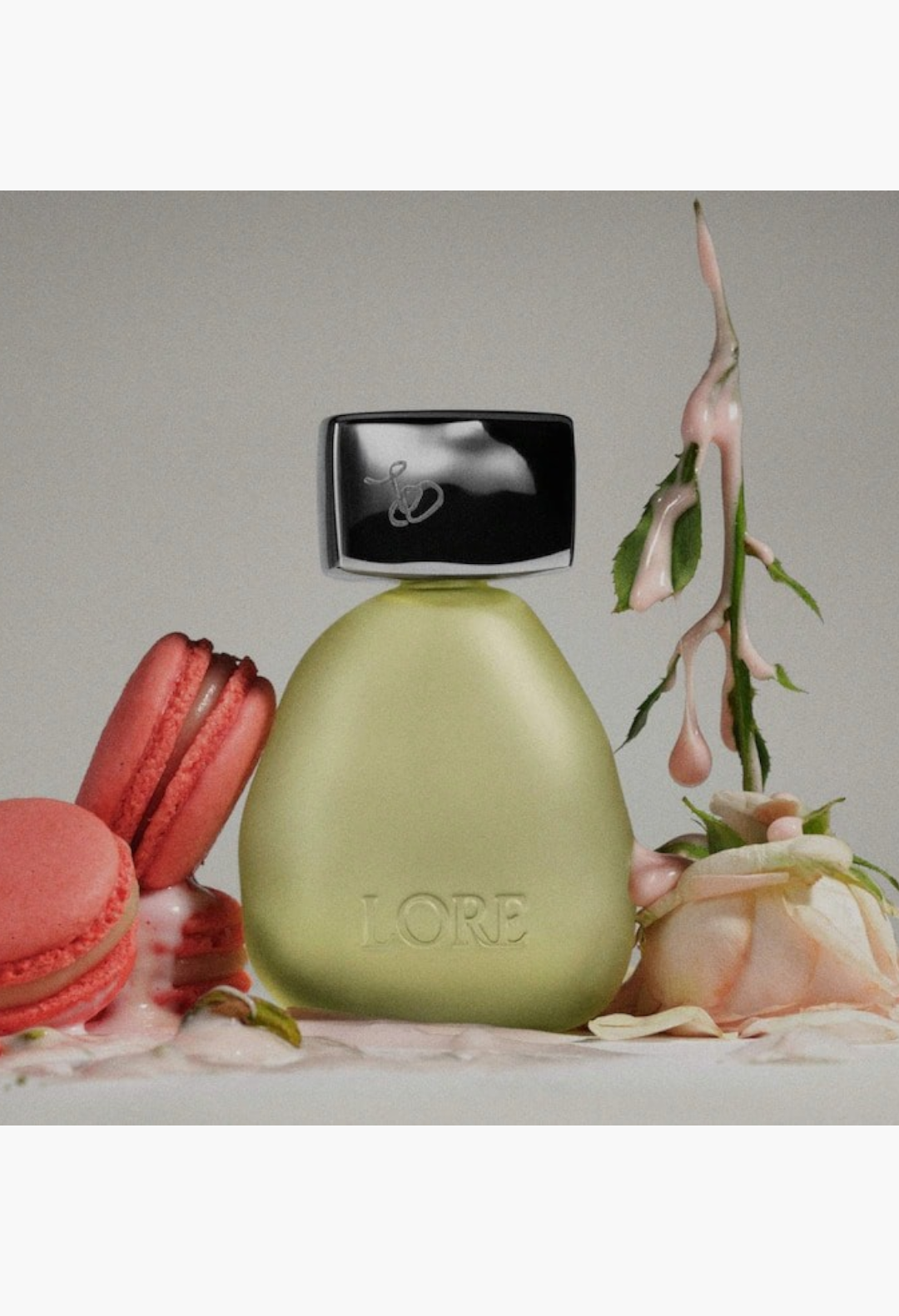 GLAM MODA LORE perfume bottle surrounded by a pink macaron and a delicate rose, showcasing a soft green glass design.