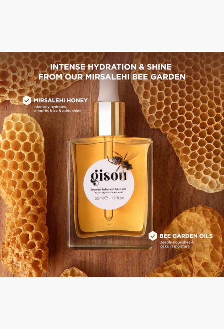 GLAM MODA Gisou honey infused hair oil bottle surrounded by natural honeycomb pieces on a wooden surface