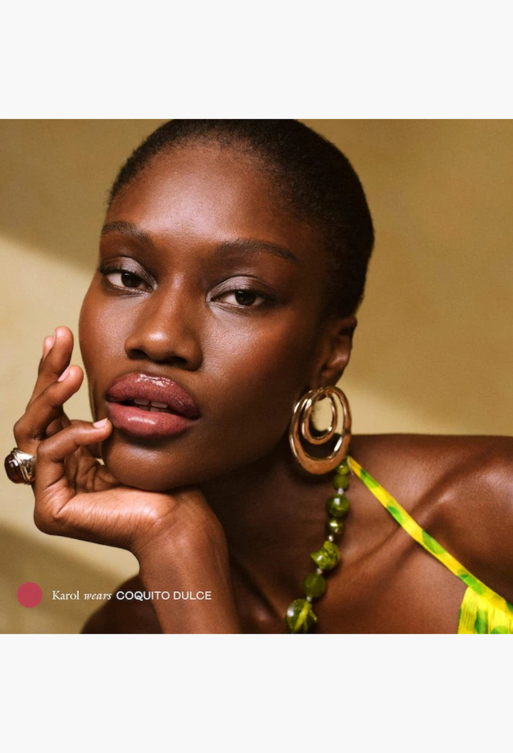 GLAM MODA model wearing Coquito Dulce peptide lip balm with a glossy, tinted finish and plump, hydrated lips.