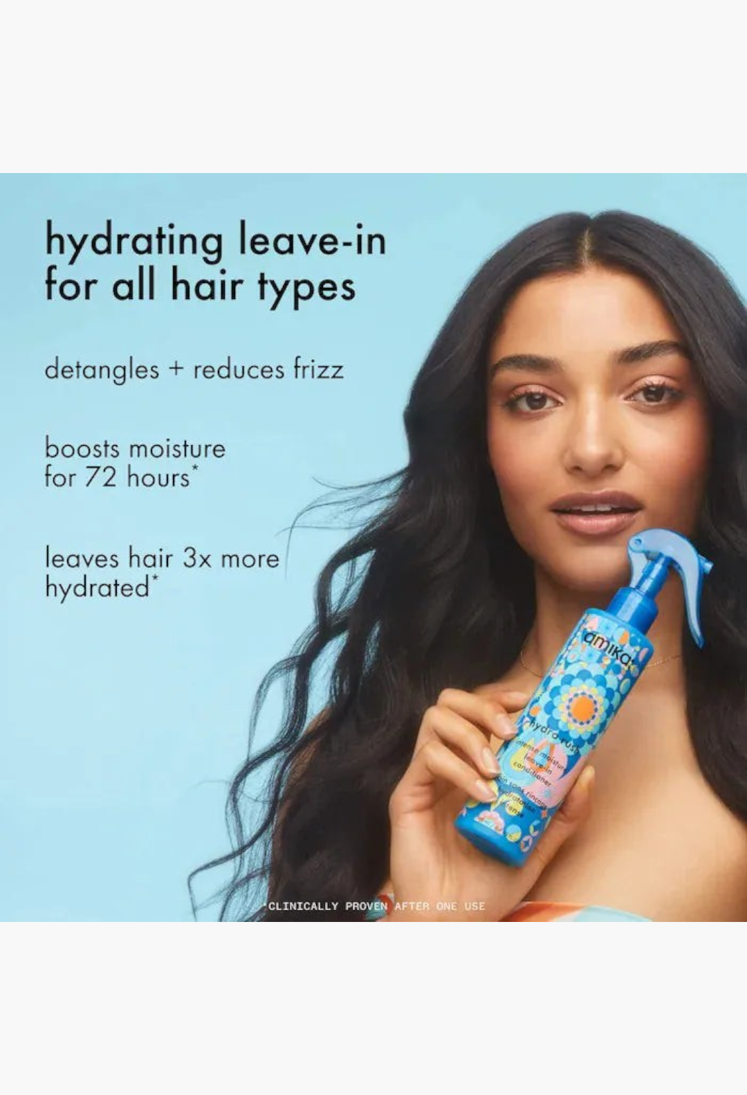 GLAM MODA model holding Amika Hydro Rush leave-in conditioner spray bottle against a light blue background