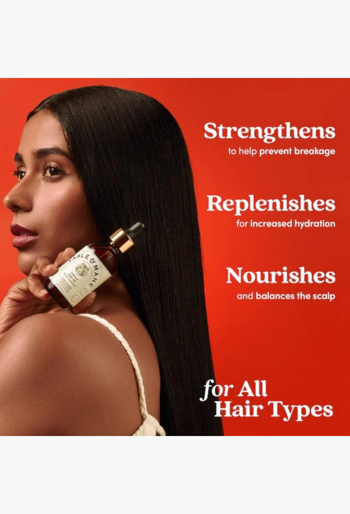 GLAM MODA model holding a bottle of Fable & Mane HoliRoots hair oil with long, sleek dark hair in a studio setting
