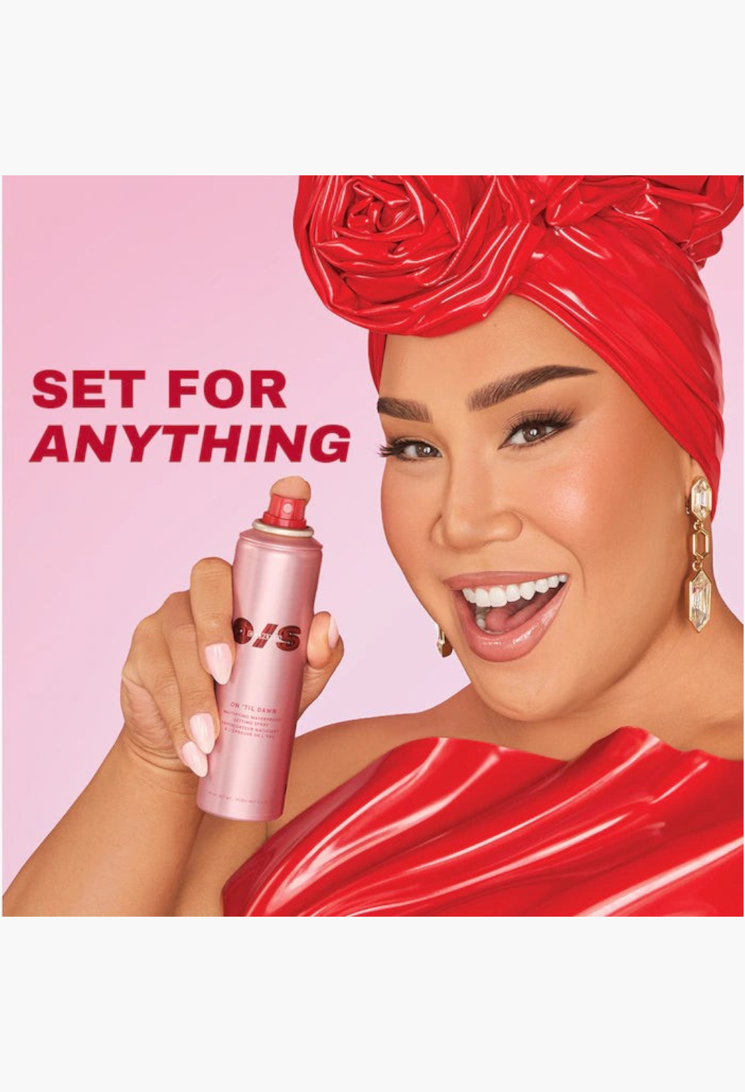 GLAM MODA model holding a pink On 'Til Dawn mattifying setting spray bottle, wearing a vibrant red headwrap and top.