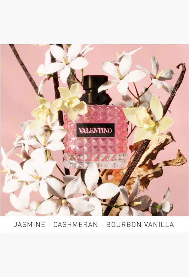 GLAM MODA Valentino Donna Born In Roma perfume bottle surrounded by white flowers and vanilla bean stalks