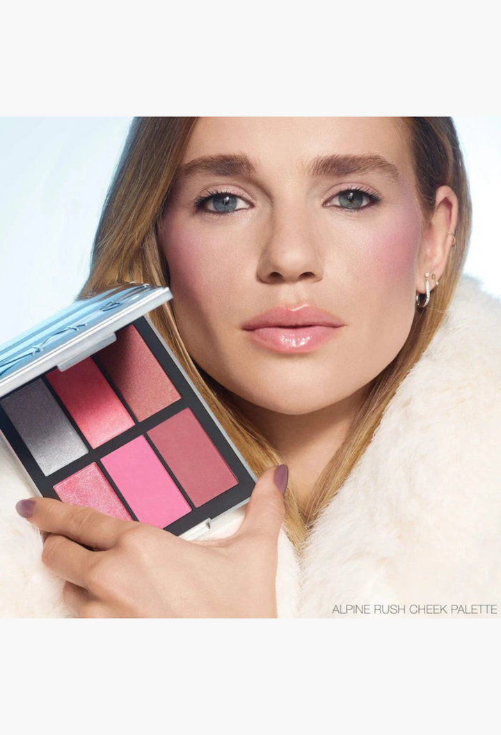 GLAM MODA Alpine Rush cheek palette featuring six rosy blush and iridescent highlighter shades held by a model