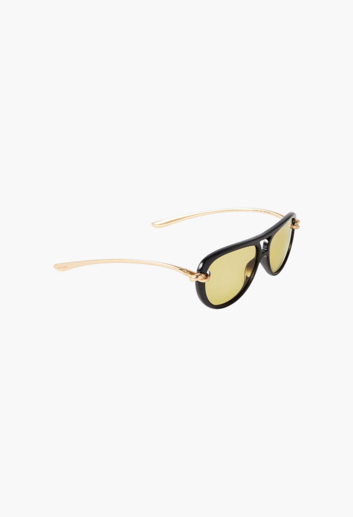 GLAM MODA New Knot aviator sunglasses featuring black frames and gold-tone twisted metal temples with yellow lenses.