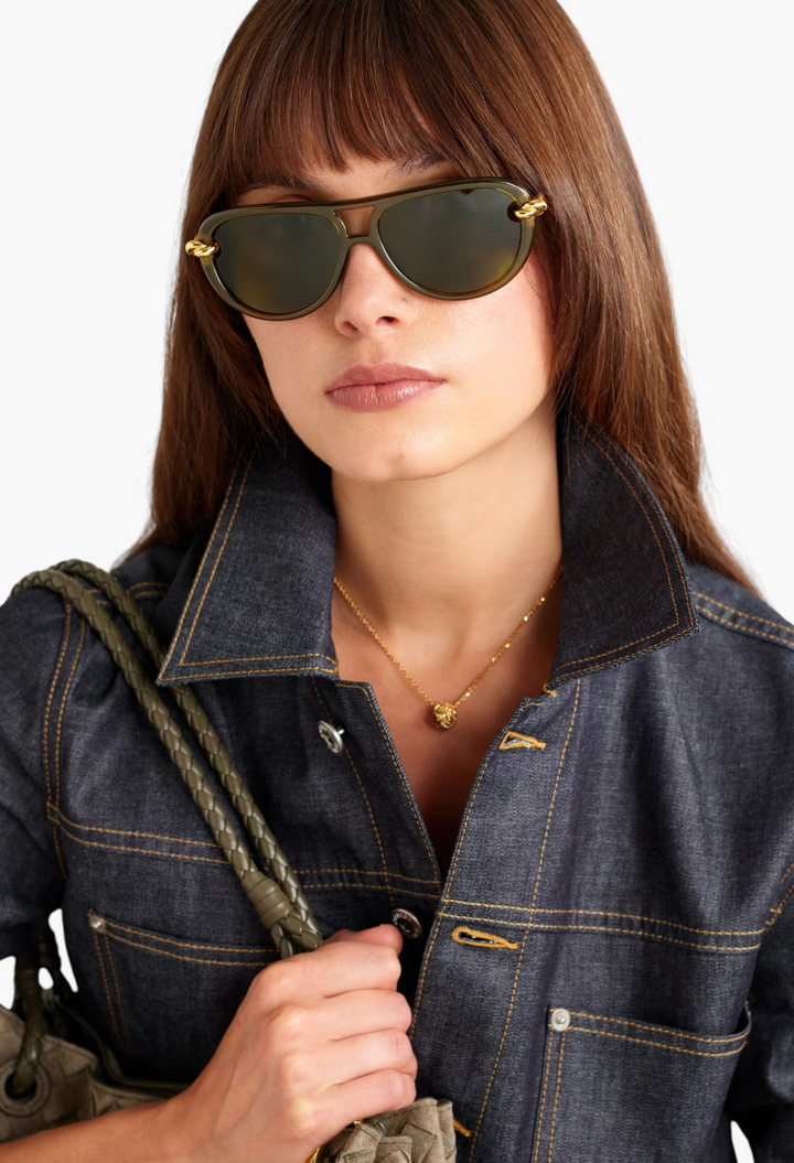 GLAM MODA New Knot aviator sunglasses in black with gold-tone twisted metal temples worn by a woman